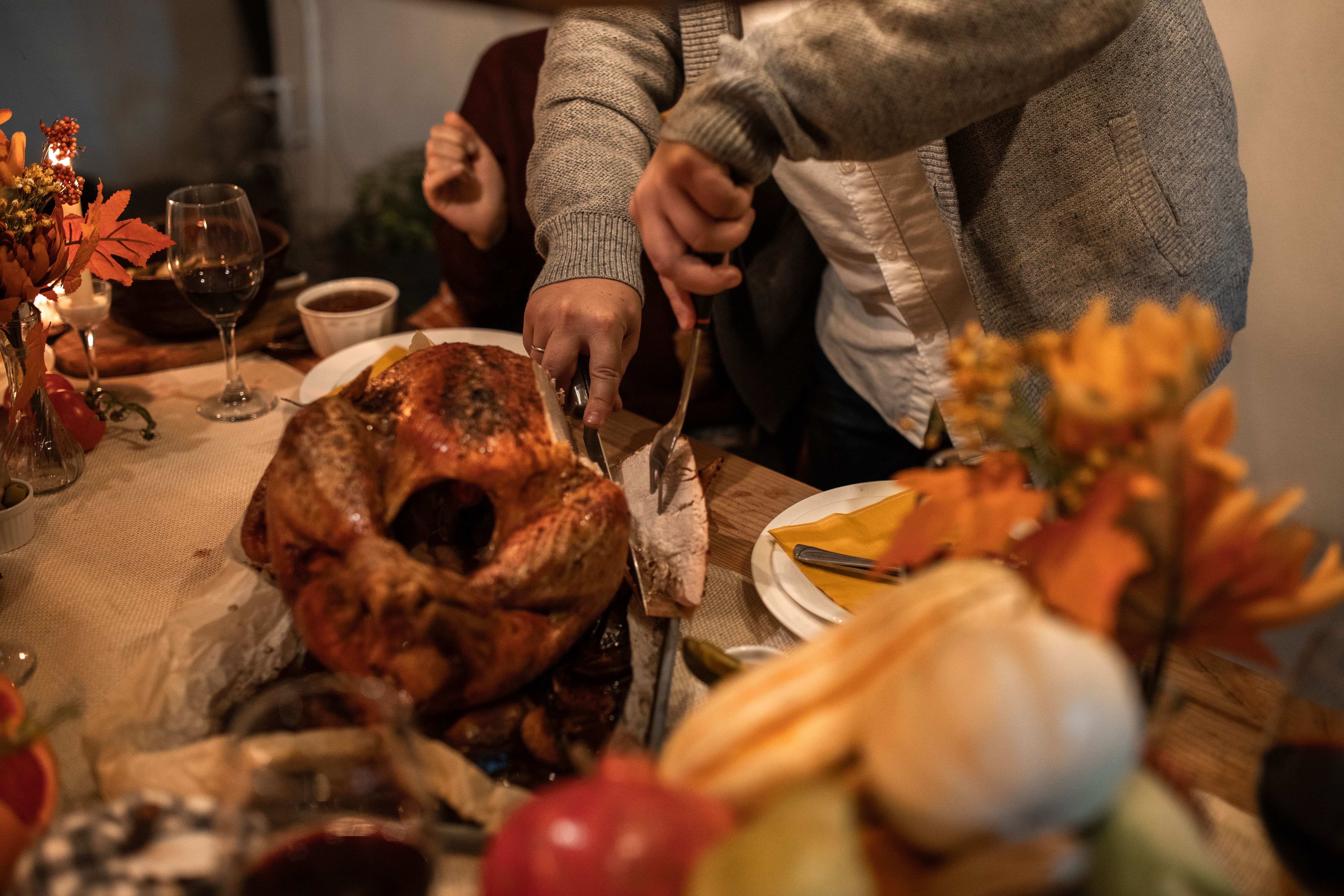 Thanksgiving turkey being carved at dining table adorned with autumn decor